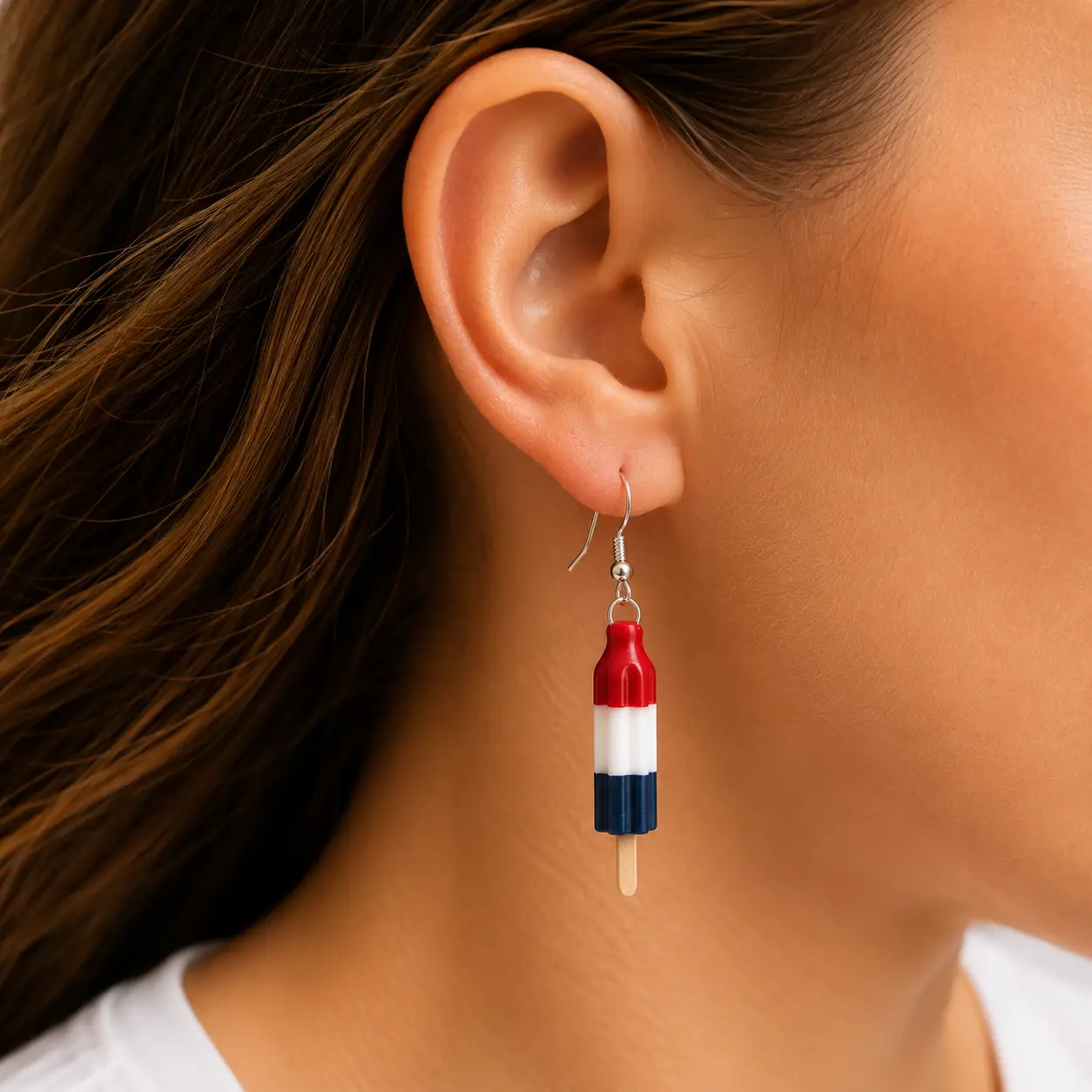 Close-up of a woman wearing handmade Bomb Pop popsicle earrings with silver hooks.
